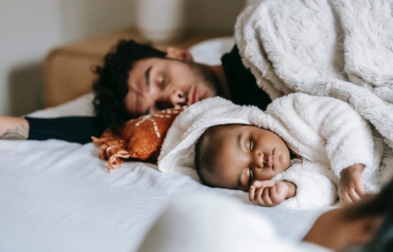 Father and infant peacefully sleeping together in bed, creating a heartwarming and bonding moment.